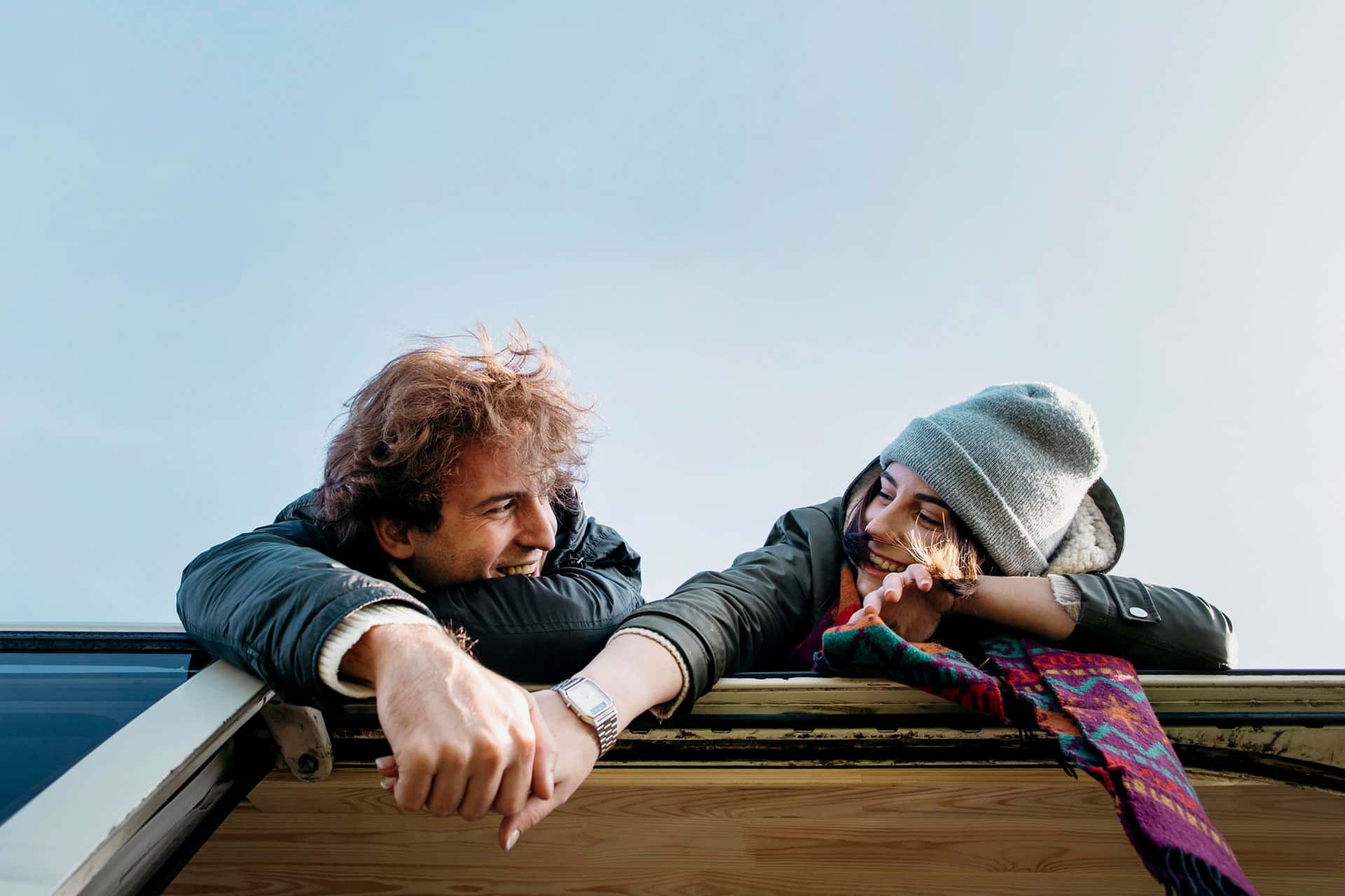 ein Personen liegen auf einem Dach und halten sich die Hände. Bildwinkel ist von unten auf sie. designed by Freepik