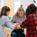 Jugendliche Schüler*innen sitzen zusammen bei einem Tisch und arbeiten gemeinsam - designed by freepik