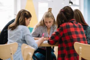 Jugendliche Schüler*innen sitzen zusammen bei einem Tisch und arbeiten gemeinsam - designed by freepik