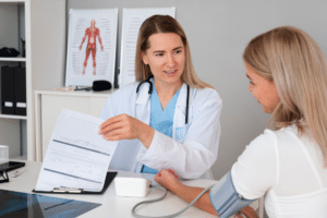 Vorsorgeuntersuchung einer Ärztin. Sie misst den Blutdruck einer Patientin und bearbeitet den Fragebogen für die Vorsorgeuntersuchung. - designed by Freepik - Magnific.com